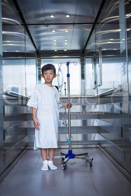 Smiling boy patient holding intravenous iv drip stand in lift