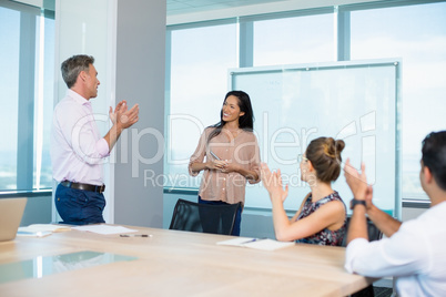 colleagues clapping for businesswoman in conference room