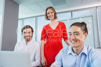 Smiling business colleagues discussing over laptop in conference room