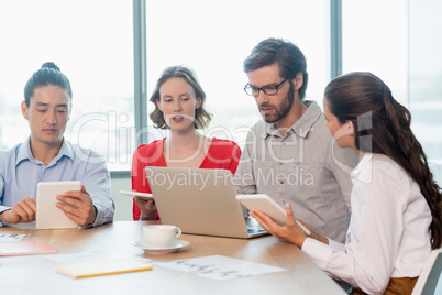 Business executives using laptop and digital tablet in conference room
