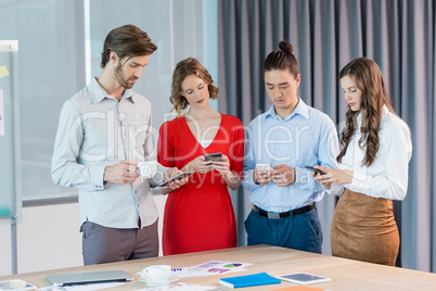 Business executives using mobile phones in conference room