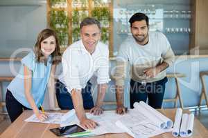 Smiling architects working over blueprint in conference room