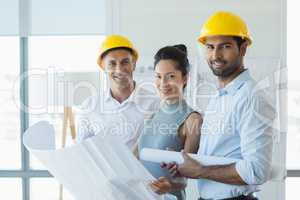 Smiling three architects standing in office with blueprint