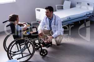 Male doctor interacting with child patient in ward