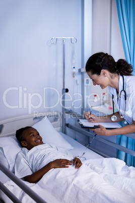 Female doctor writing on clipboard while interacting with patient