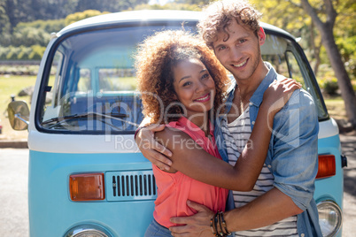 Smiling couple standing in front of campervan