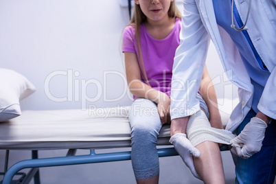 Doctor putting bandage on injured leg of patient