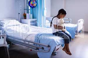 Patient sitting on bed with teddy bear