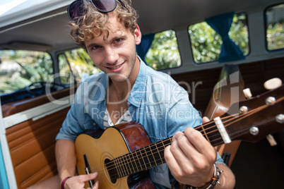 Man playing guitar in campervan
