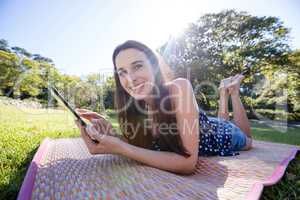Smiling woman lying on mat and using digital tablet