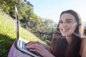 Portrait of woman lying on mat and using laptop