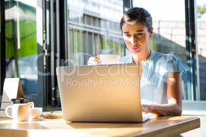 Female executive working on laptop in cafÃ?Â©