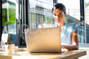 Female executive working on laptop in cafÃ?Â©