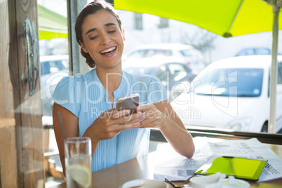 Female executive using mobile phone in cafÃ?Â©
