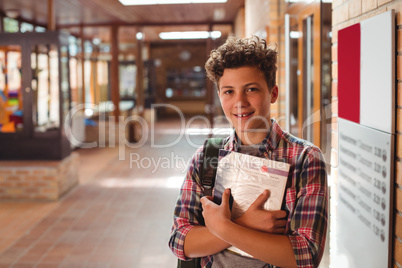 Portrait of schoolboy holding notebook in corridor