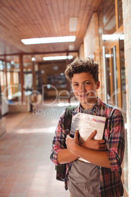 Portrait of schoolboy holding notebook in corridor