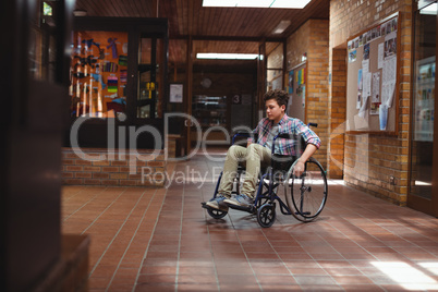 Disabled schoolboy on wheelchair in corridor at school