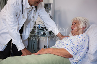 Doctor examining senior patient in ward