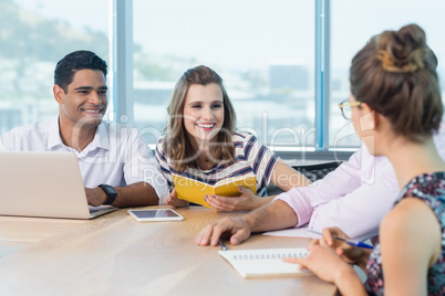 Smiling business colleagues interacting with each other in meeting