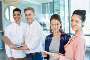 Portrait of confident architects holding laptop and digital tablet