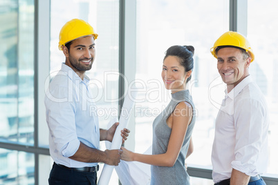 Smiling three architects standing in office with blueprint