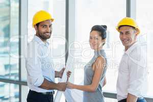 Smiling three architects standing in office with blueprint