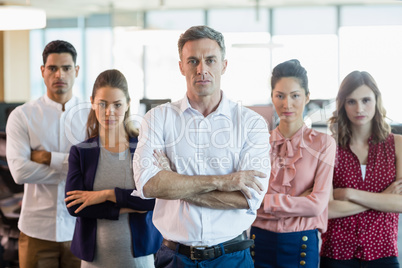 Business executives with arms crossed standing in office