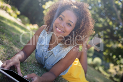 Woman lying on grass and using digital tablet