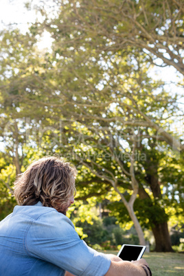 Man sitting on grass using digital tablet