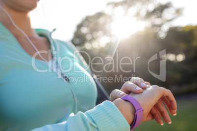 Mid section of female jogger checking her fitness band