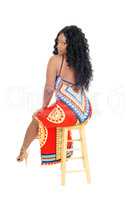 African woman sitting in long dress.