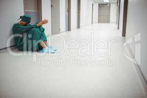 Tensed female surgeon sitting in corridor