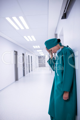 Tensed female surgeon standing in corridor