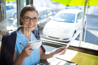 Female executive looking at document while having coffee
