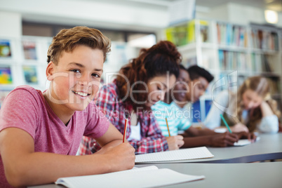 Portrait of happy schoolboy studying in library