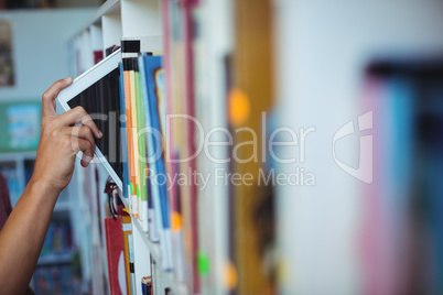 Hand of student keeping digital tablet in bookshelf in library