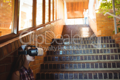 Schoolgirl using virtual reality headset on staircase