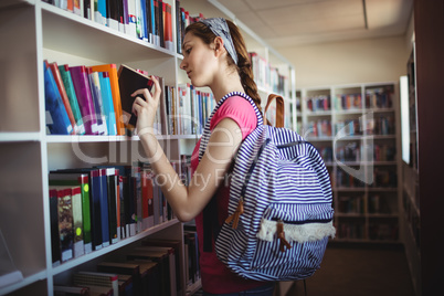 Schoolgirl selecting book in library