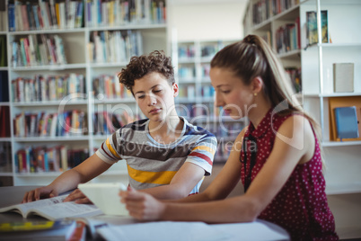 Classmates using digital tablet in library