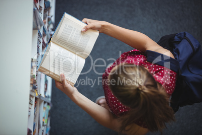 High angle view of attentive schoolgirl reading book in library