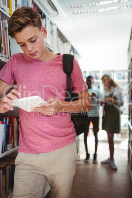 Attentive schoolboy using digital tablet in library Attentive schoolboy using digital tablet in library