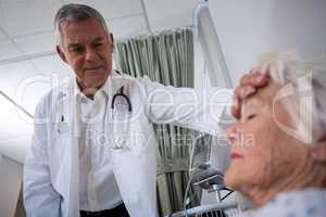 Doctor examining senior patient in ward