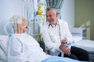 Doctor interacting with senior patient in ward