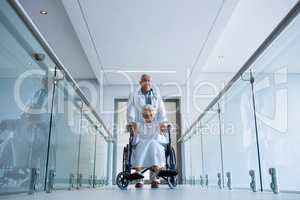 Doctor holding senior patient on wheelchair in passageway