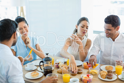 Business colleagues interacting with each other while having breakfast