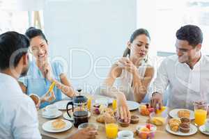 Business colleagues interacting with each other while having breakfast