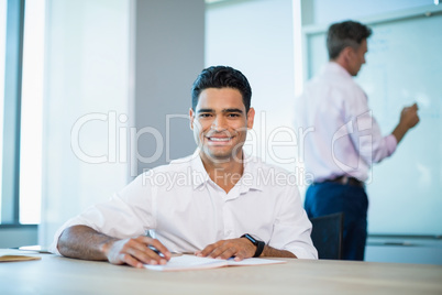 Portrait of smiling business executive writing on notebook in conference room