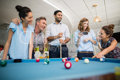 Smiling business colleagues playing pool