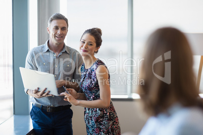 Smiling business colleagues discussing over laptop