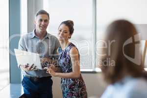 Smiling business colleagues discussing over laptop